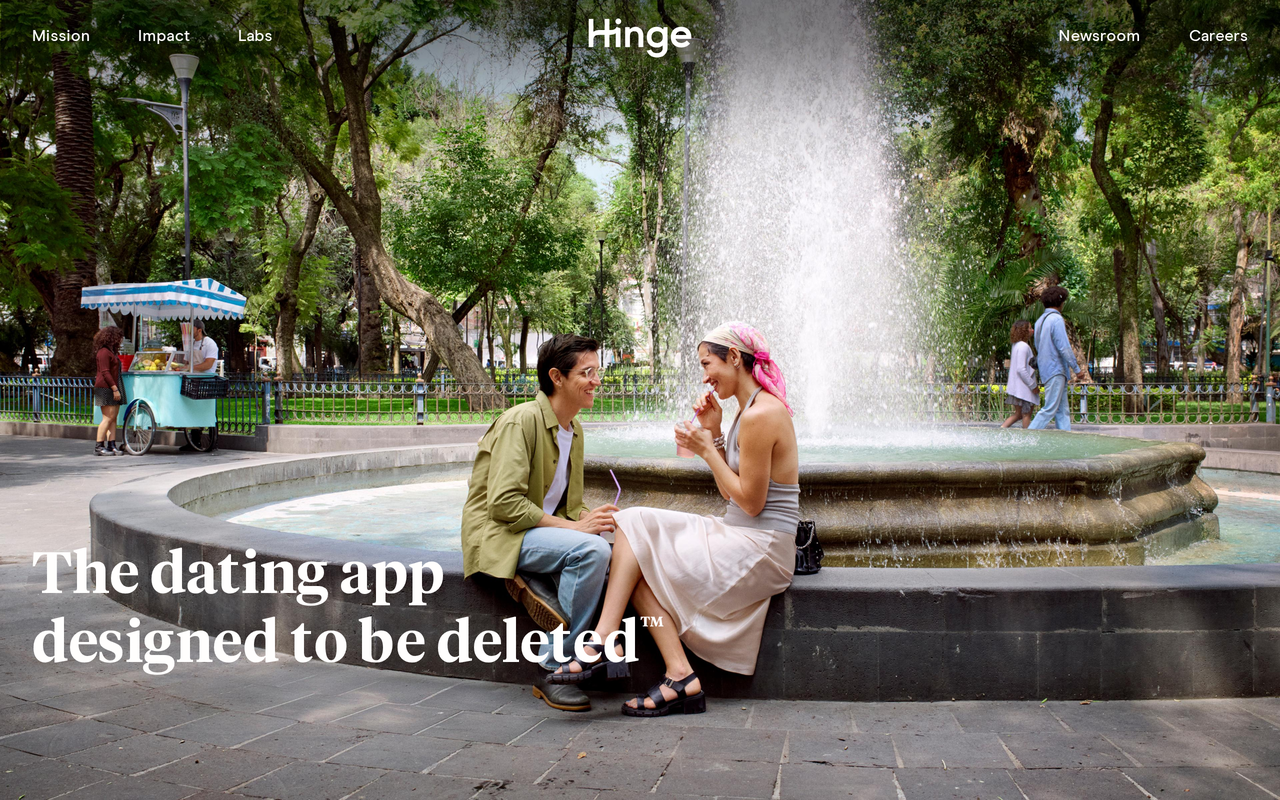 Hinge homepage showing a couple sitting on the edge of a park fountain under the tagline 'The dating app designed to be deleted'.