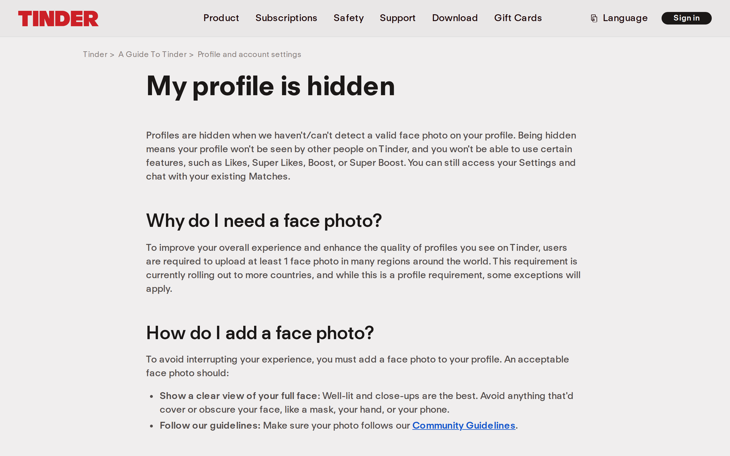 Tinder help center page titled My profile is hidden, explaining that profiles are hidden when Tinder cannot detect a valid face photo, and that an acceptable face photo must show a clear view of your full face, well lit, avoiding anything that covers or obscures it such as a mask, your hand, or your phone.